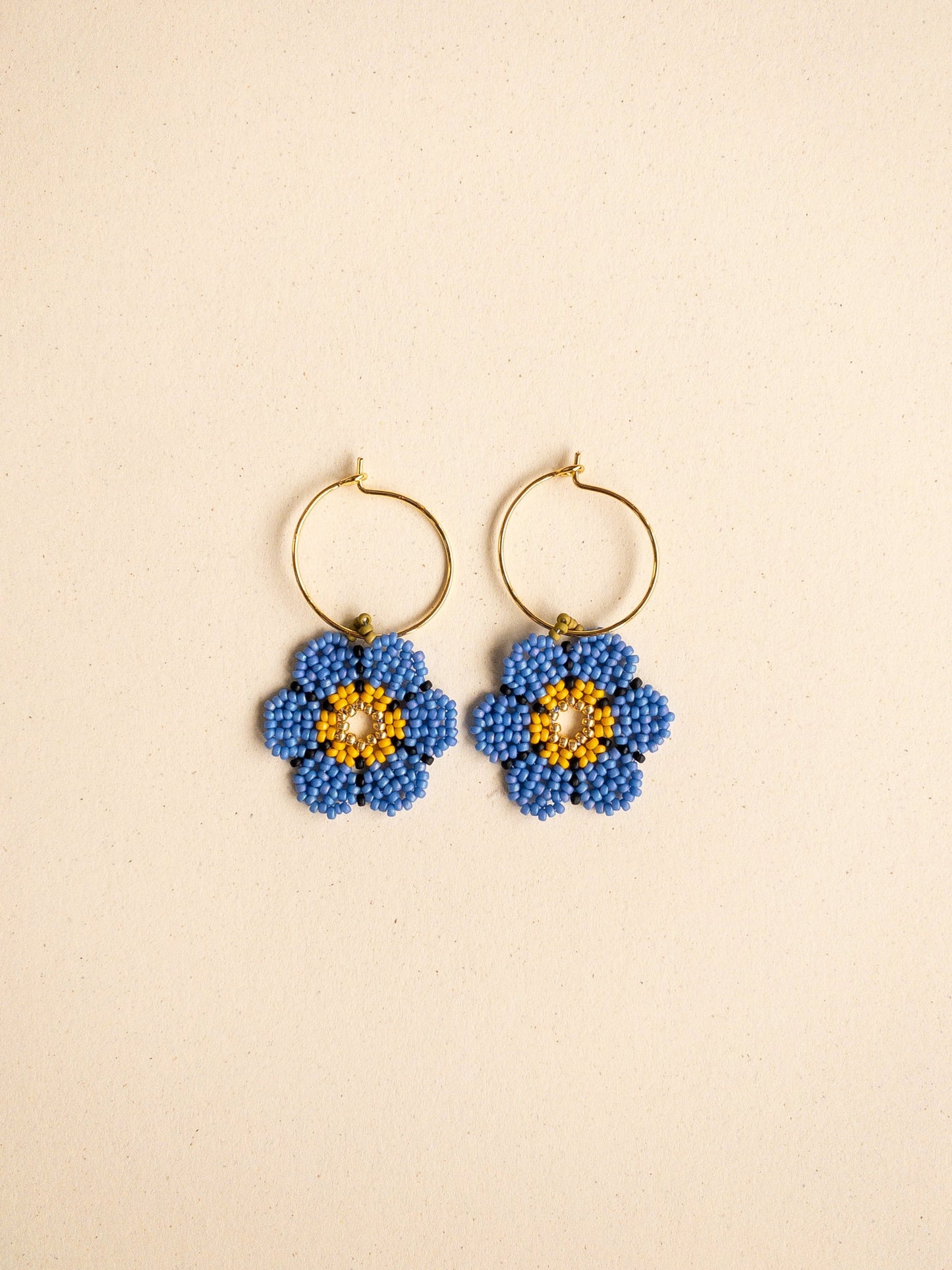 Hoop earrings with beaded daisy charms in blue.